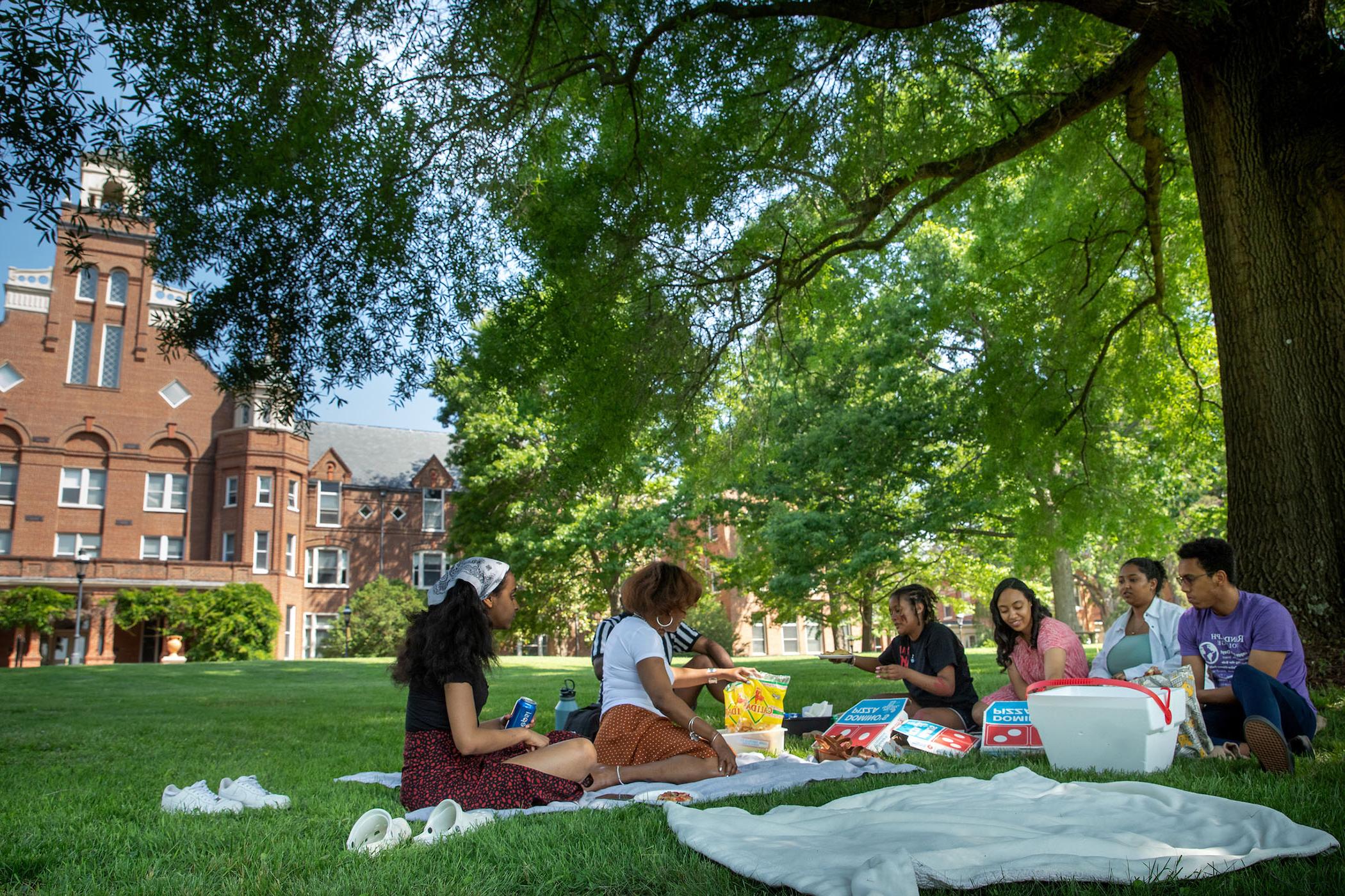 365亚洲版学院，学生们在校园前的树荫下野餐.